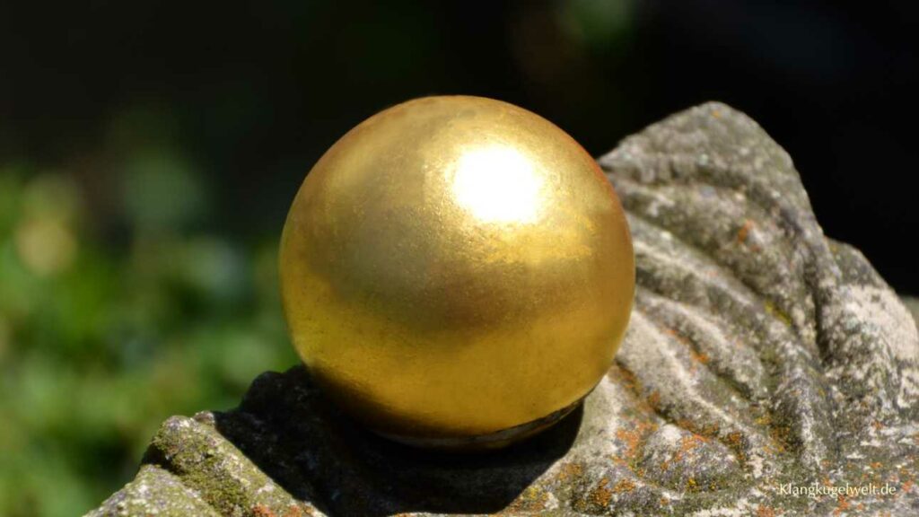 Eine goldene Kugel liegt auf einem verwitterten Stein.