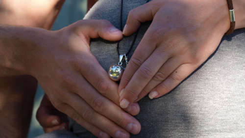 Die Hände von einem Mann und einer Frau liegen auf einem Schwangerschaftsbauch